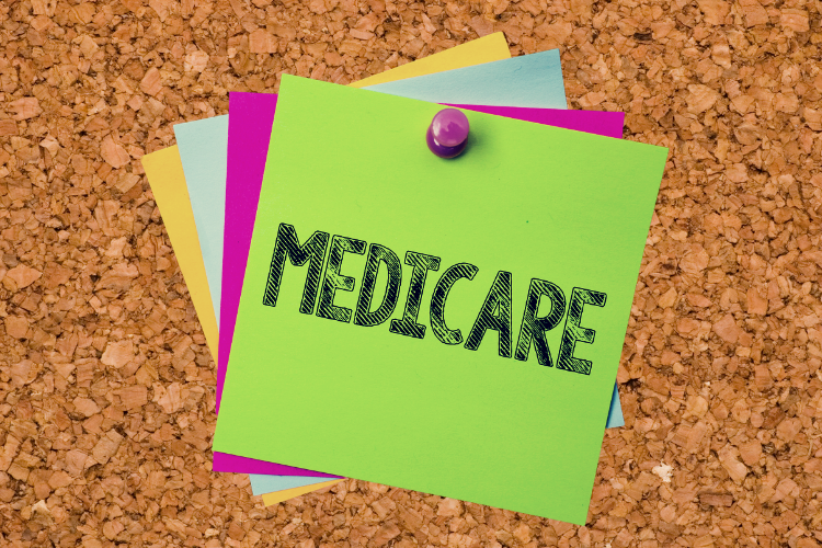 A corkboard with a post it that reads "Medicare"