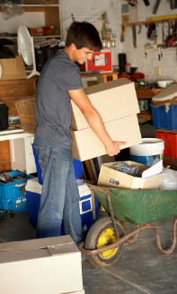 Photo of a young man moving boxes in a home garage.