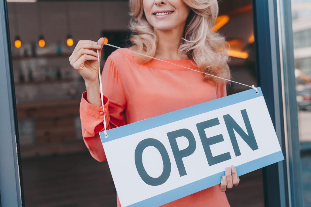 cropped shot of happy small business owner holding sign open